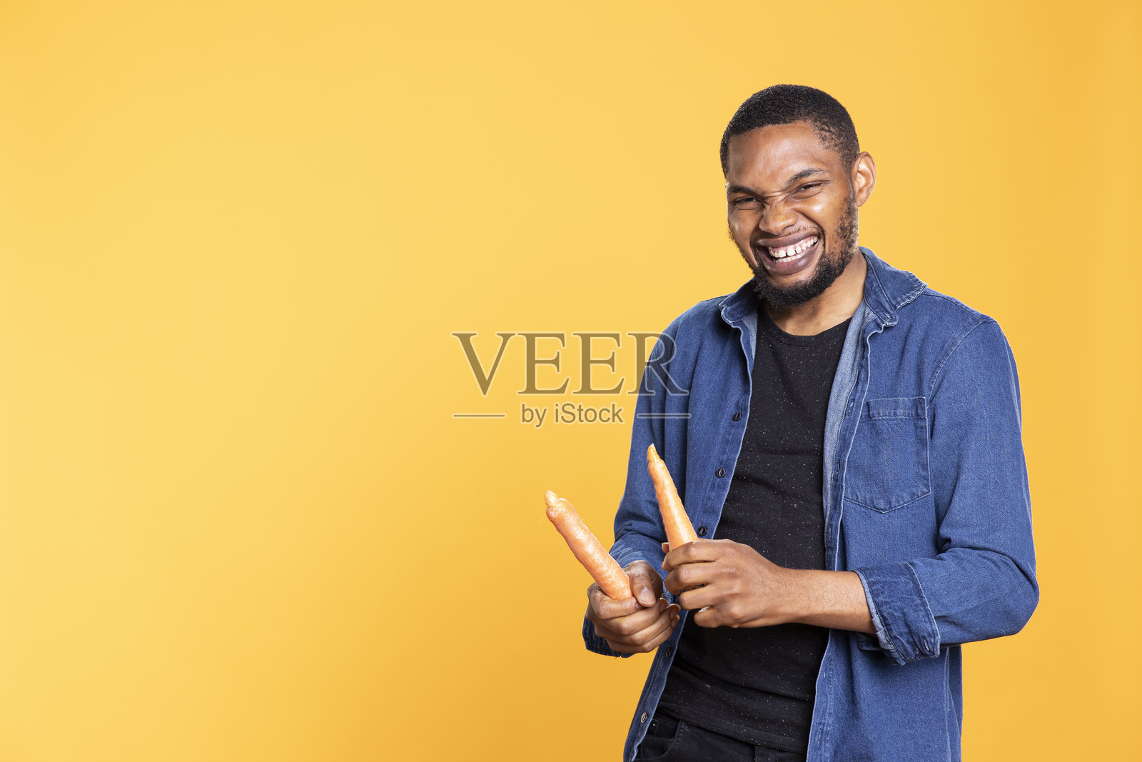 一个精力充沛的非裔美国人拿着胡萝卜假装打鼓照片摄影图片