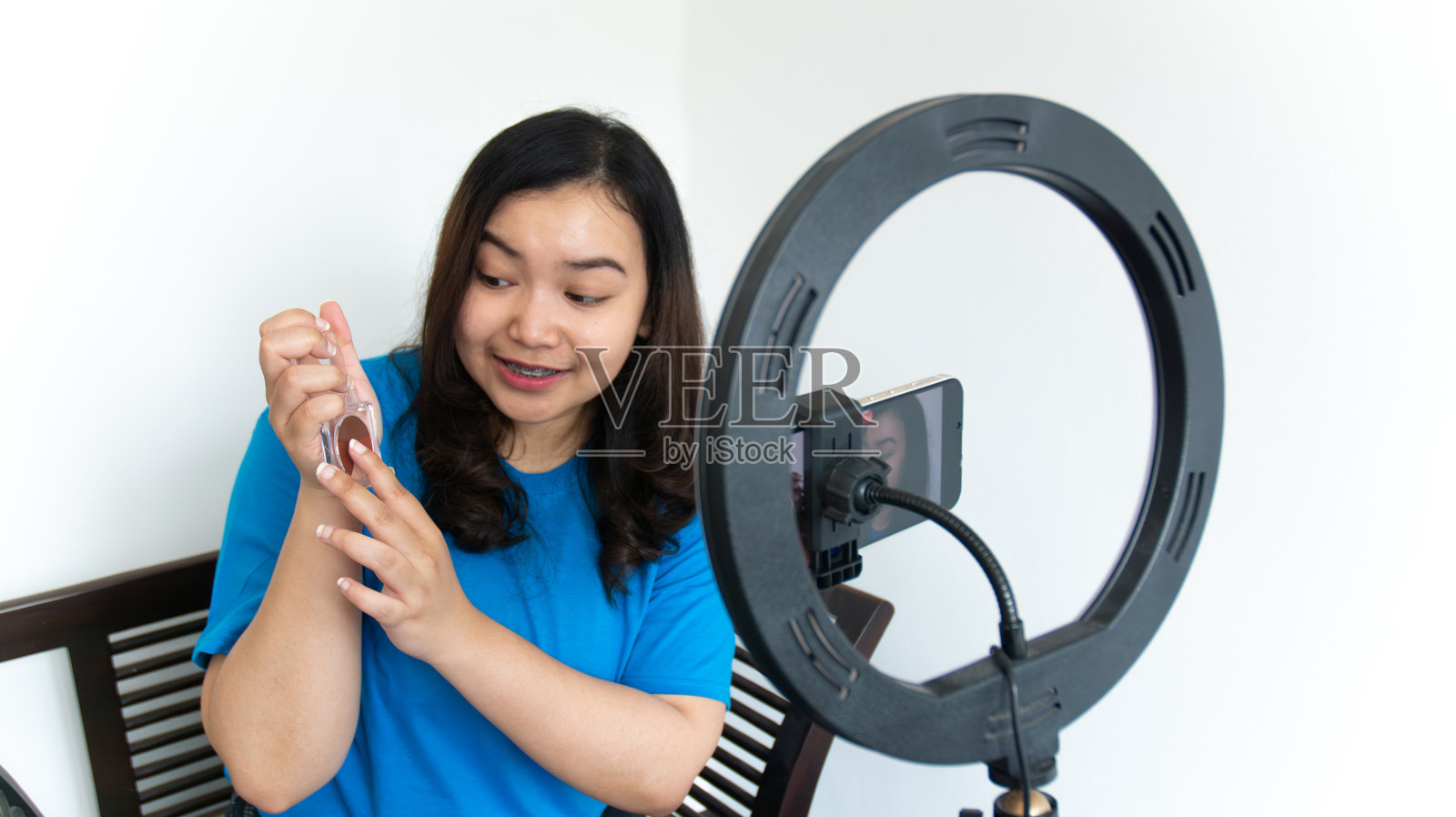 一名年轻的亚洲女性在白色背景下制作社交媒体视频。社交媒体影响概念照片摄影图片