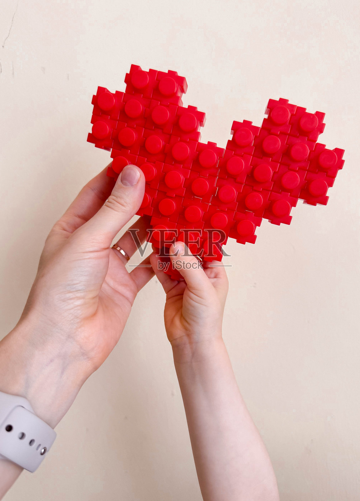 全家福，母亲和孩子的手拿着一颗用玩具制作的心。照片摄影图片