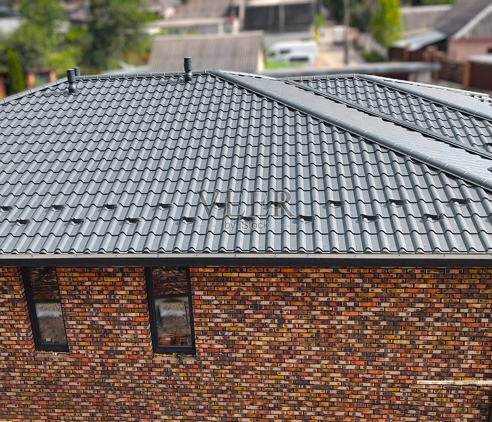 近距离房屋屋顶与钢屋面板。灰色模块瓦效果屋面板。传统的金属瓦。异型金属波纹板，如粘土或混凝土板。建筑的覆盖照片摄影图片