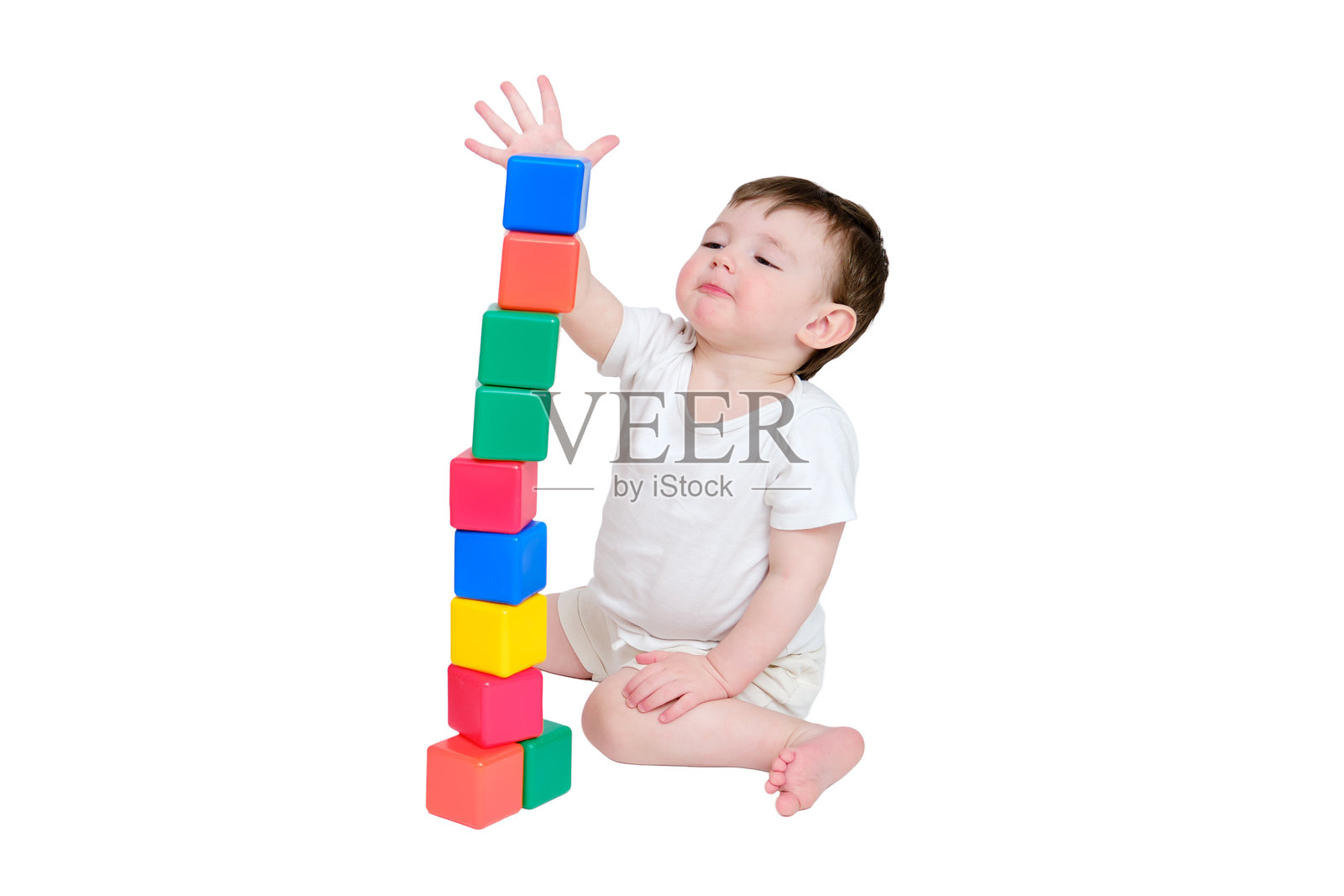 快乐的宝宝在工作室里玩教育玩具，孤立在白色的背景上。一个微笑的孩子坐在地板上玩耍的画像。2岁左右(1岁9个月)照片摄影图片