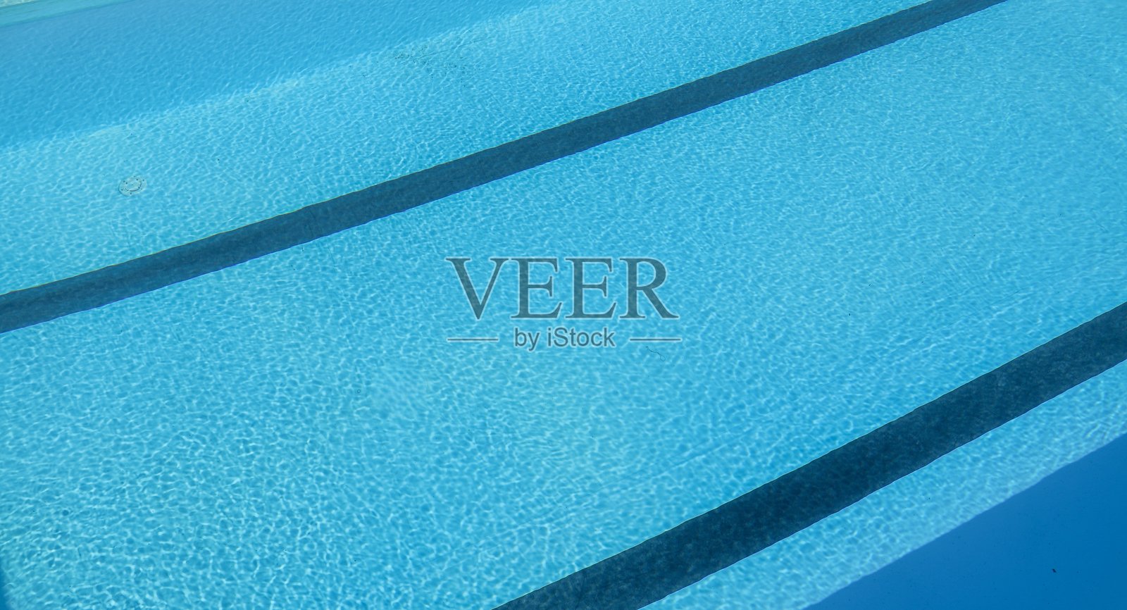 游泳池有蓝色的水和阳光反射。游泳池背景照片摄影图片