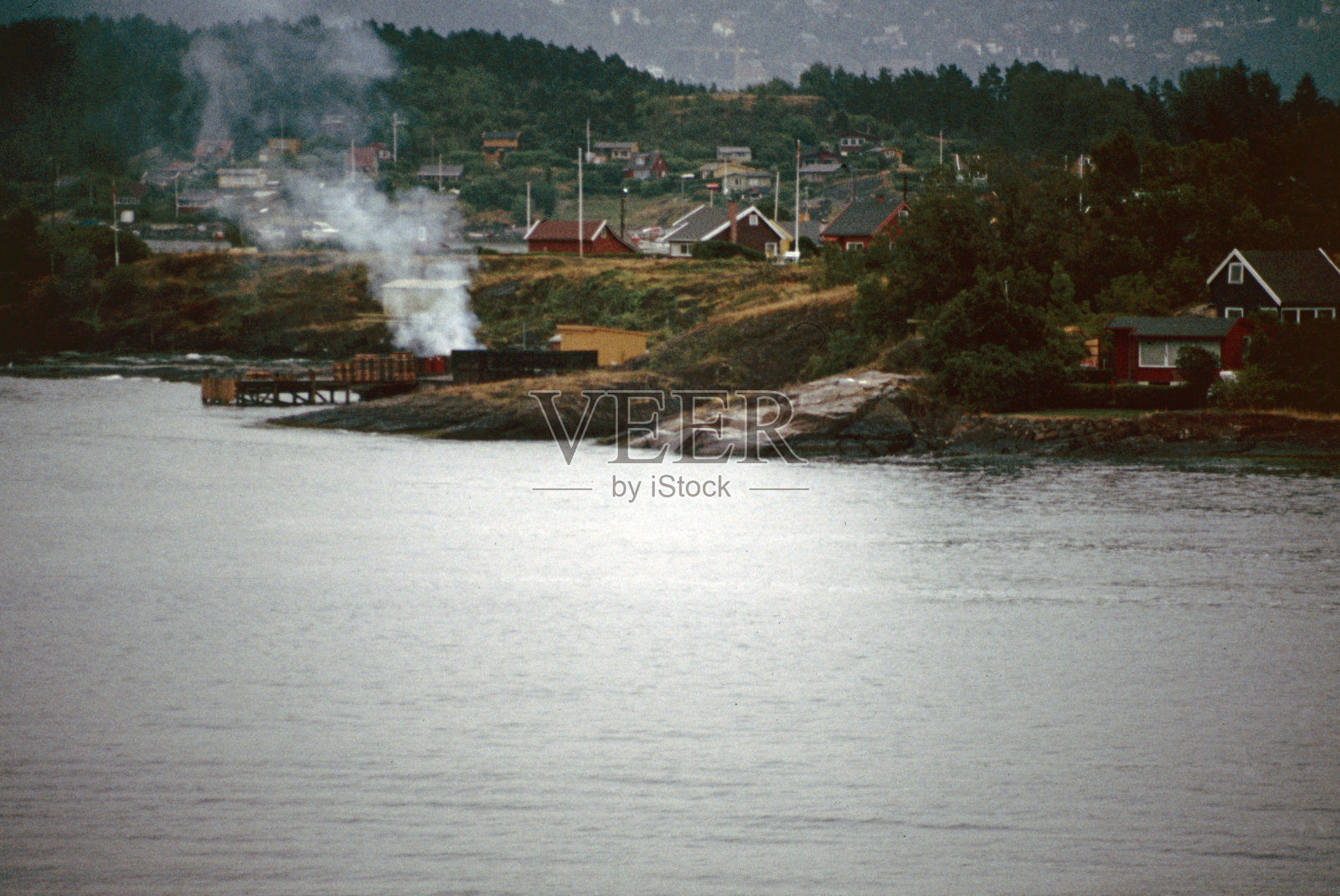 船几乎到了奥斯陆峡湾的尽头，沿岸有许多典型的房屋和篝火照片摄影图片
