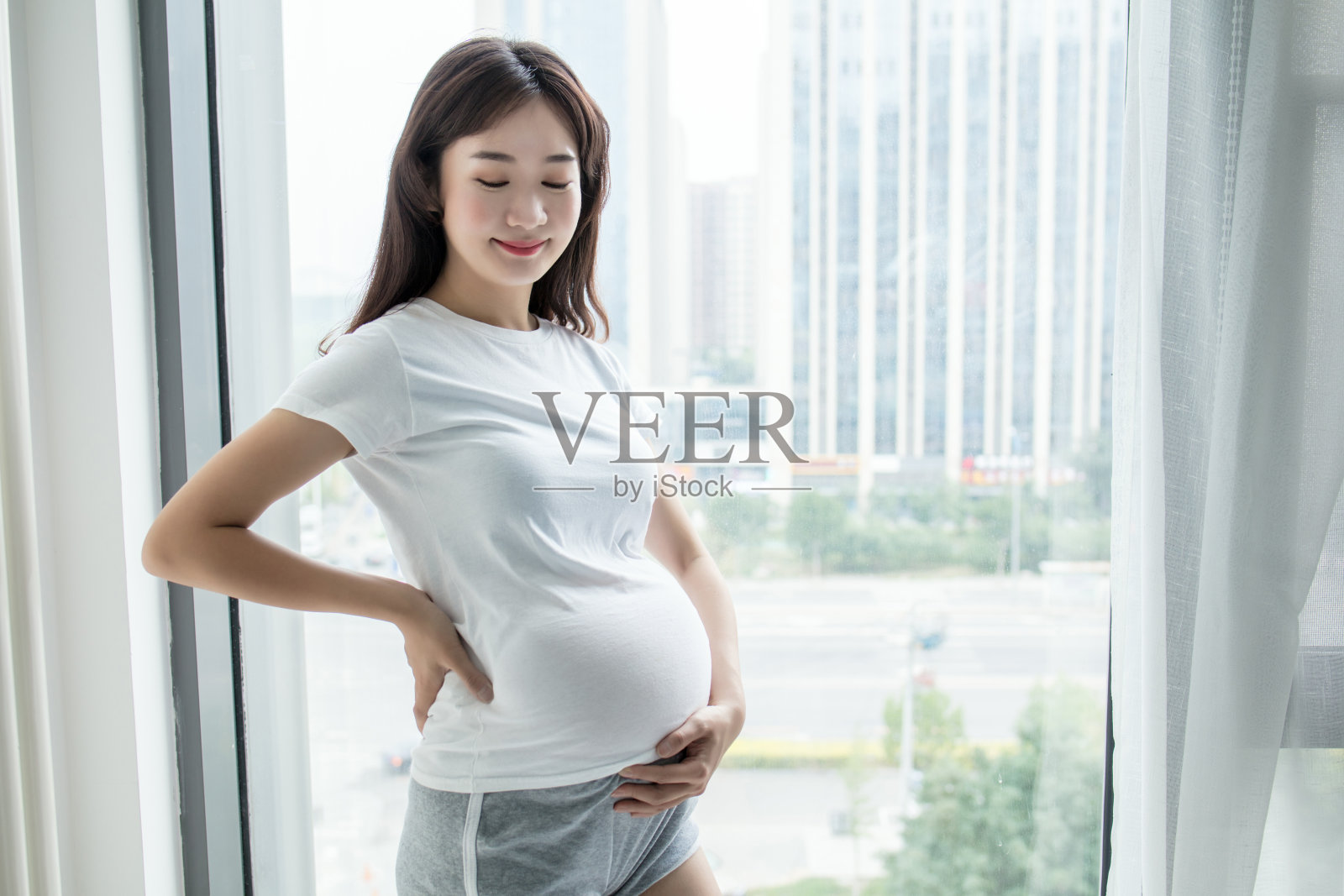 孕妇靠窗站着照片摄影图片