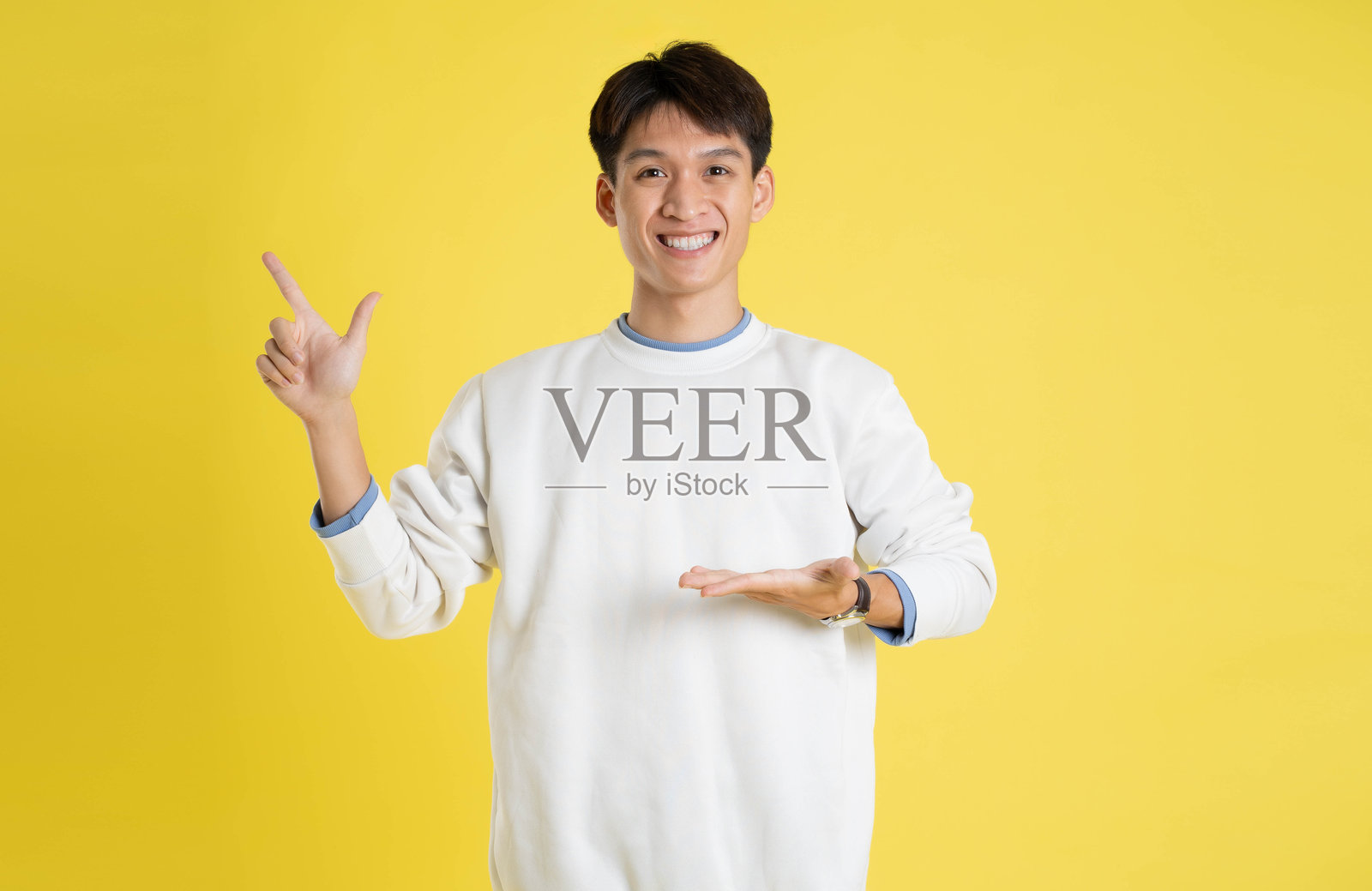 穿着毛衣的年轻亚洲男子在黄色背景上摆姿势的肖像照片摄影图片