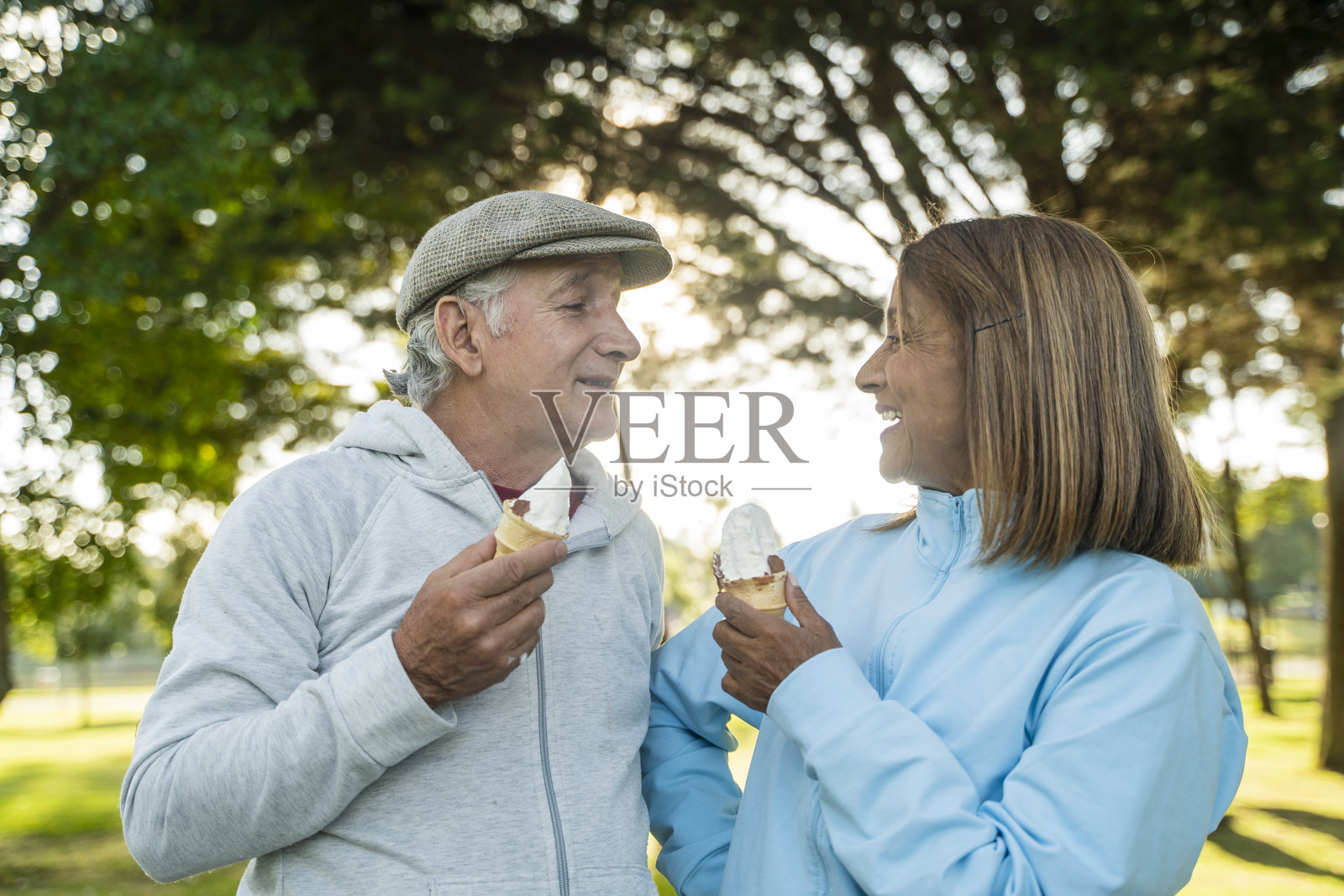 一对老夫妇运动后坐在公园里分享冰淇淋。照片摄影图片