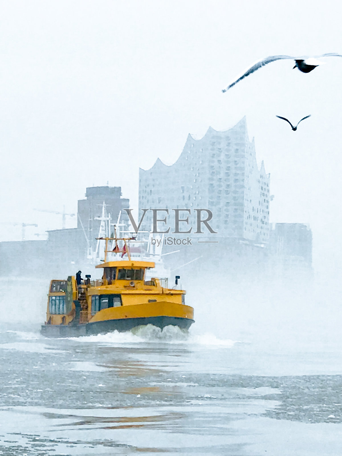 Iphone的联赛。冬天，汉堡港的易北河上冰冷多雾的天气，背景是易北爱乐音乐厅。照片摄影图片