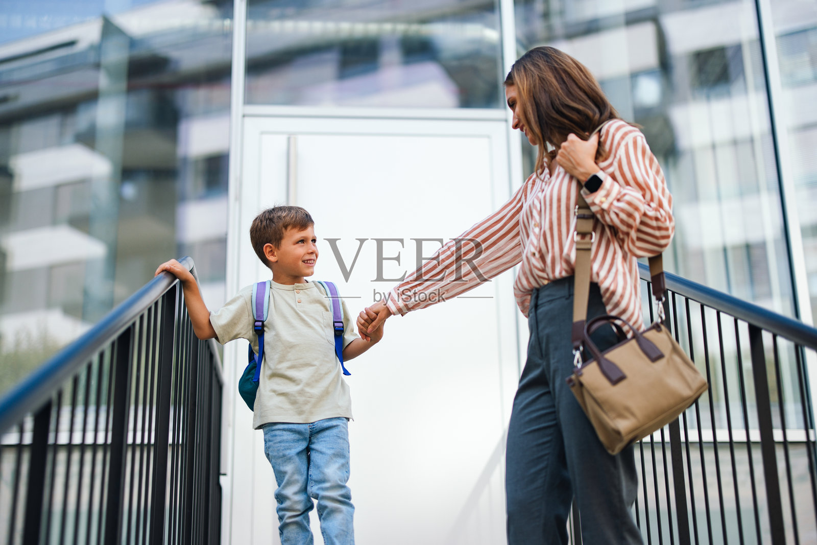 母亲和儿子在一个晴朗的早晨步行上学照片摄影图片