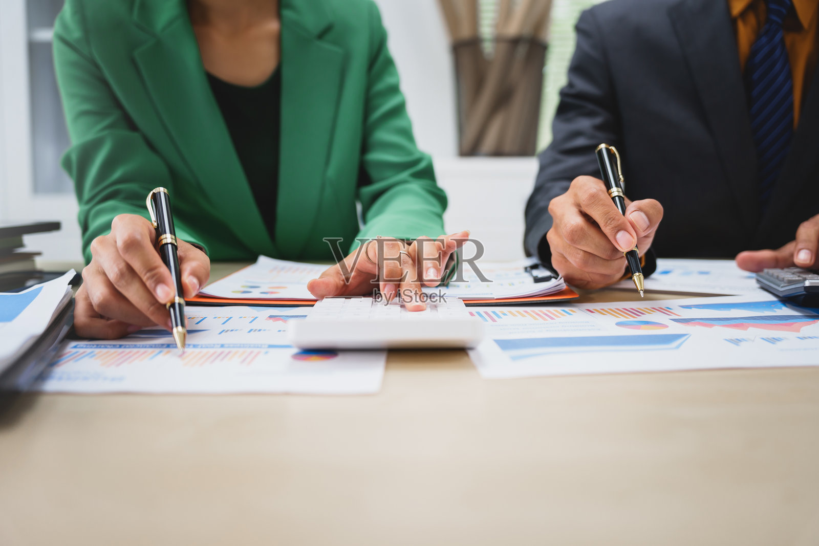 亚洲业务团队进行协作会议，财务图表在桌子上。他们穿着正式的西装，集思广益，以提高公司业绩和团队凝聚力。照片摄影图片