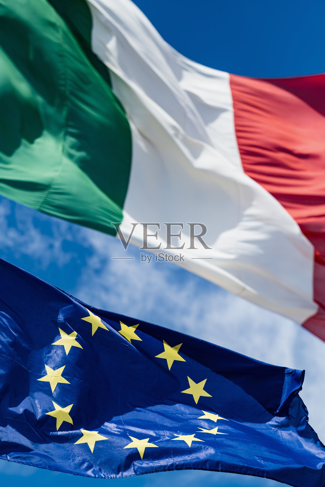 欧洲和意大利的旗帜在蓝天中飘扬。垂直的构图。照片摄影图片