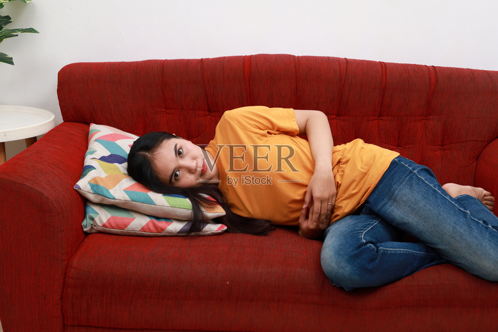 快乐的亚洲女人拥抱腹部躺在沙发上照片摄影图片