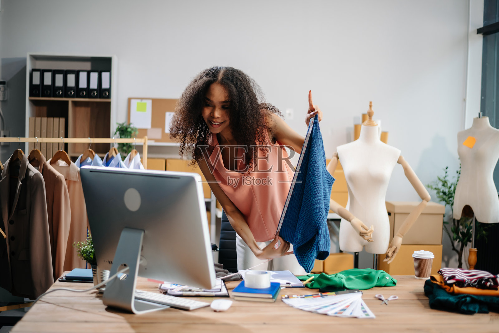 成功的时装设计师。有吸引力的年轻亚洲女子站在车间微笑。漂亮的女老板在工作照片摄影图片