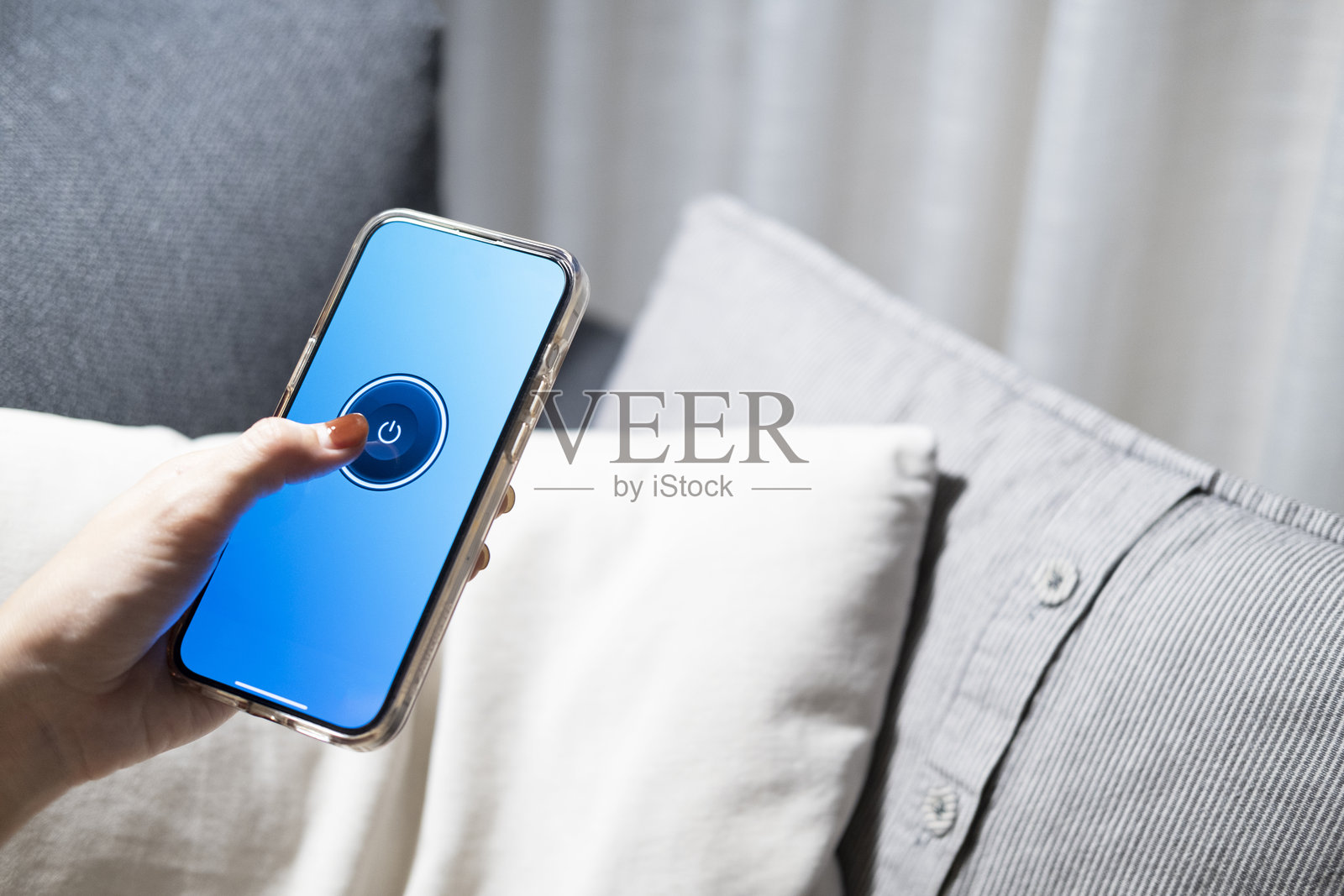 智能家居概念通过移动应用程序控制灯光、灯具或家用电器。女人的手是通过她在床上或沙发上的手机关掉灯照片摄影图片