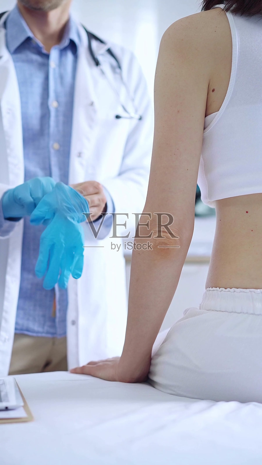 医生和病人。戴上蓝色手套的医生准备在诊所检查女病人。医学整形外科照片摄影图片