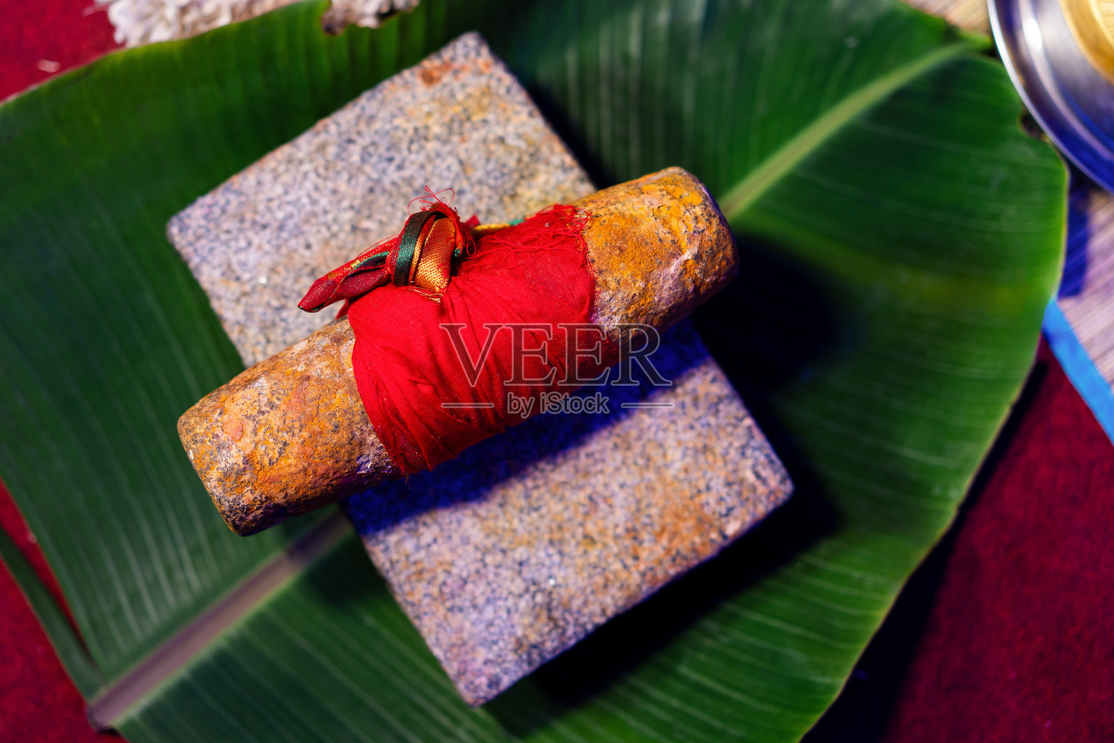 传统的巴丹磨石，用姜黄粉和红色织物绑在香蕉叶上，在印度婚礼仪式上使用。照片摄影图片