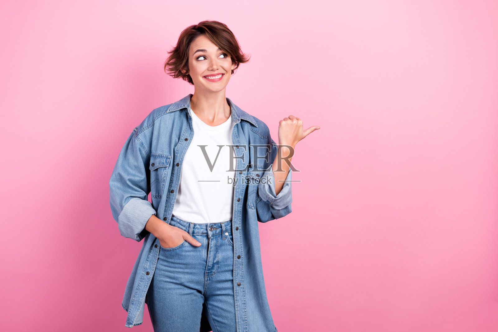 照片的年轻开朗的积极的广告穿着时尚的模特鲍勃棕色的头发直接手指出口衣服孤立在粉红色的背景照片摄影图片