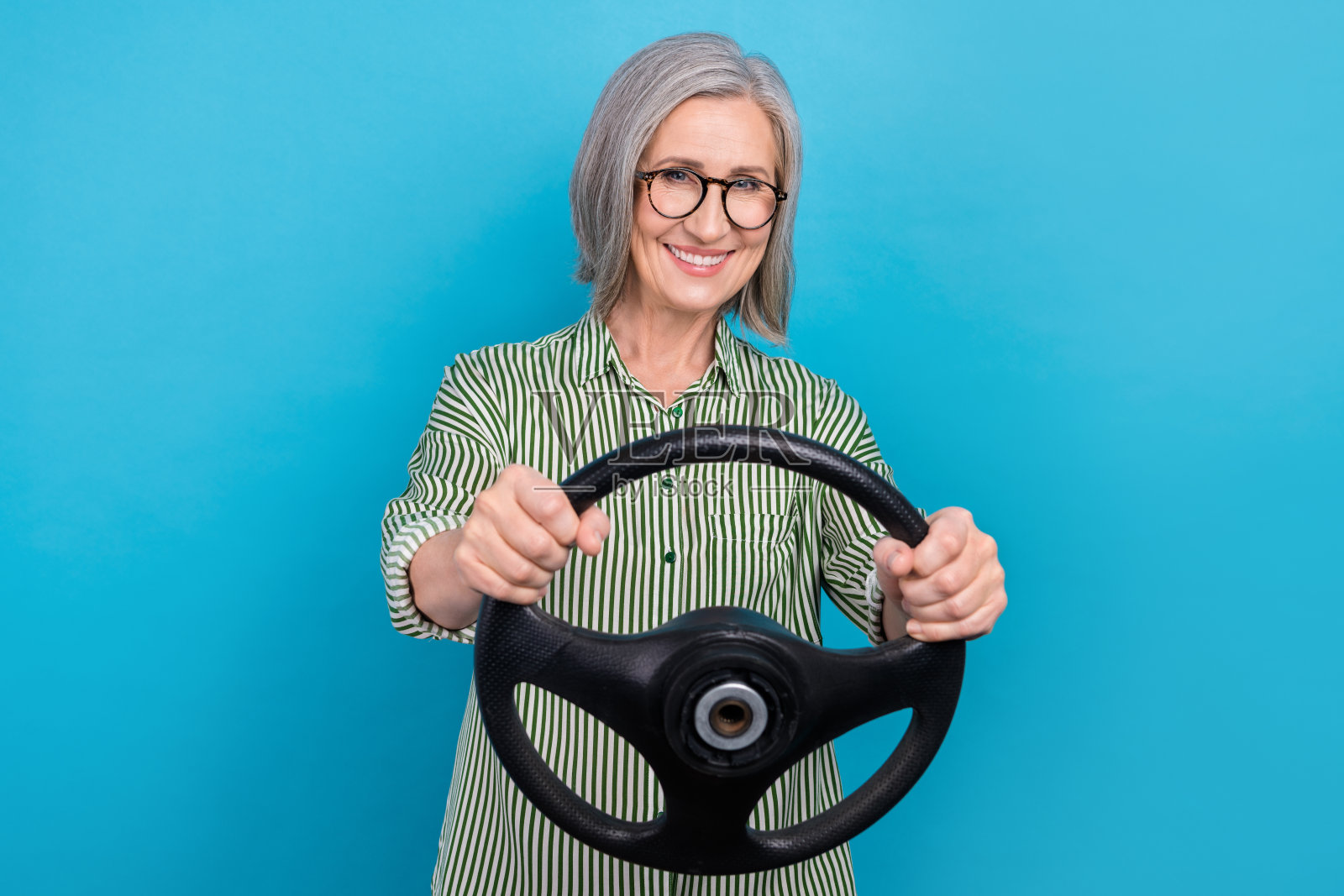 照片中老年成熟年龄白发正装制服女士驾驶新车主方向盘正常速度孤立在蓝色背景照片摄影图片