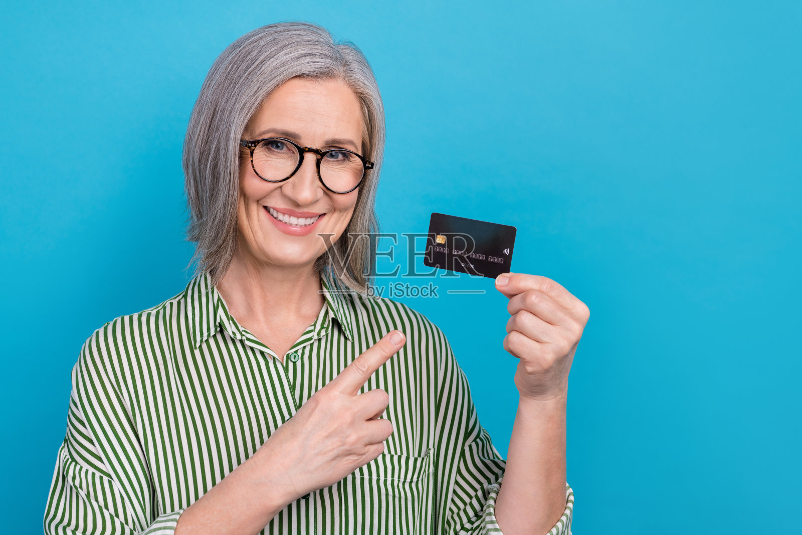 迷人的开朗的女士的照片表明，手指，手握借记卡孤立的蓝色背景照片摄影图片