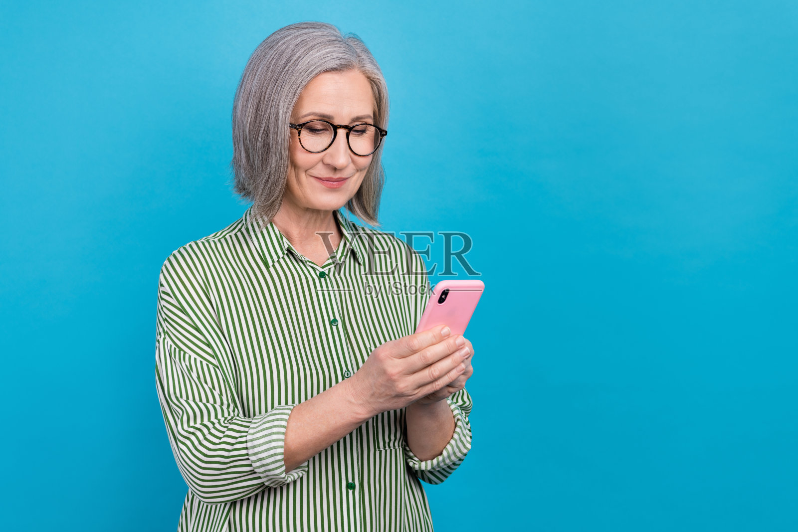 有吸引力的积极女士的肖像使用智能手机打字空白空间隔离在蓝色背景照片摄影图片