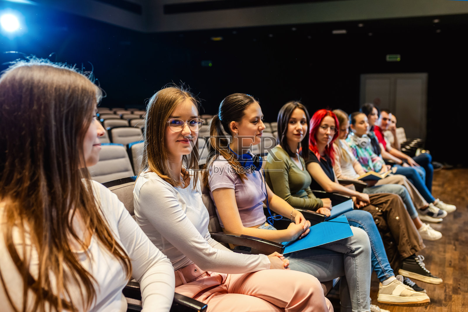 女学生在圆形剧场听讲座。照片摄影图片