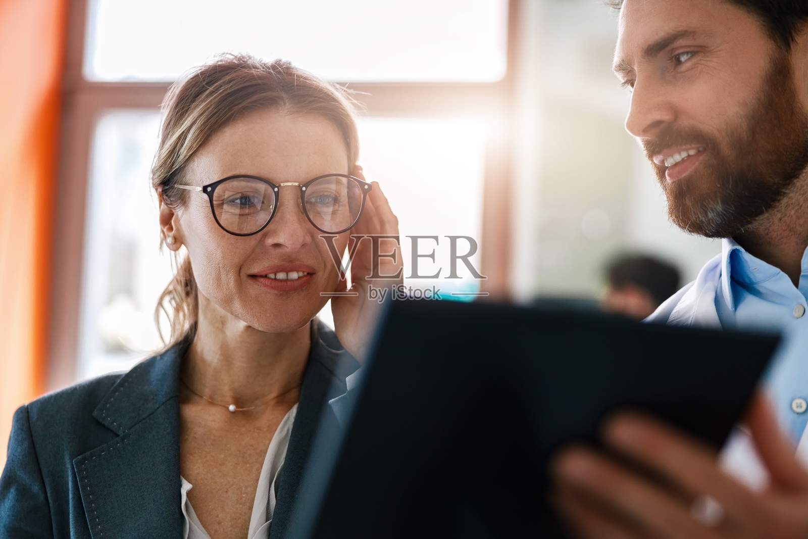 验光师在眼镜店帮女士挑选眼镜的近照，对着她的镜子照片摄影图片