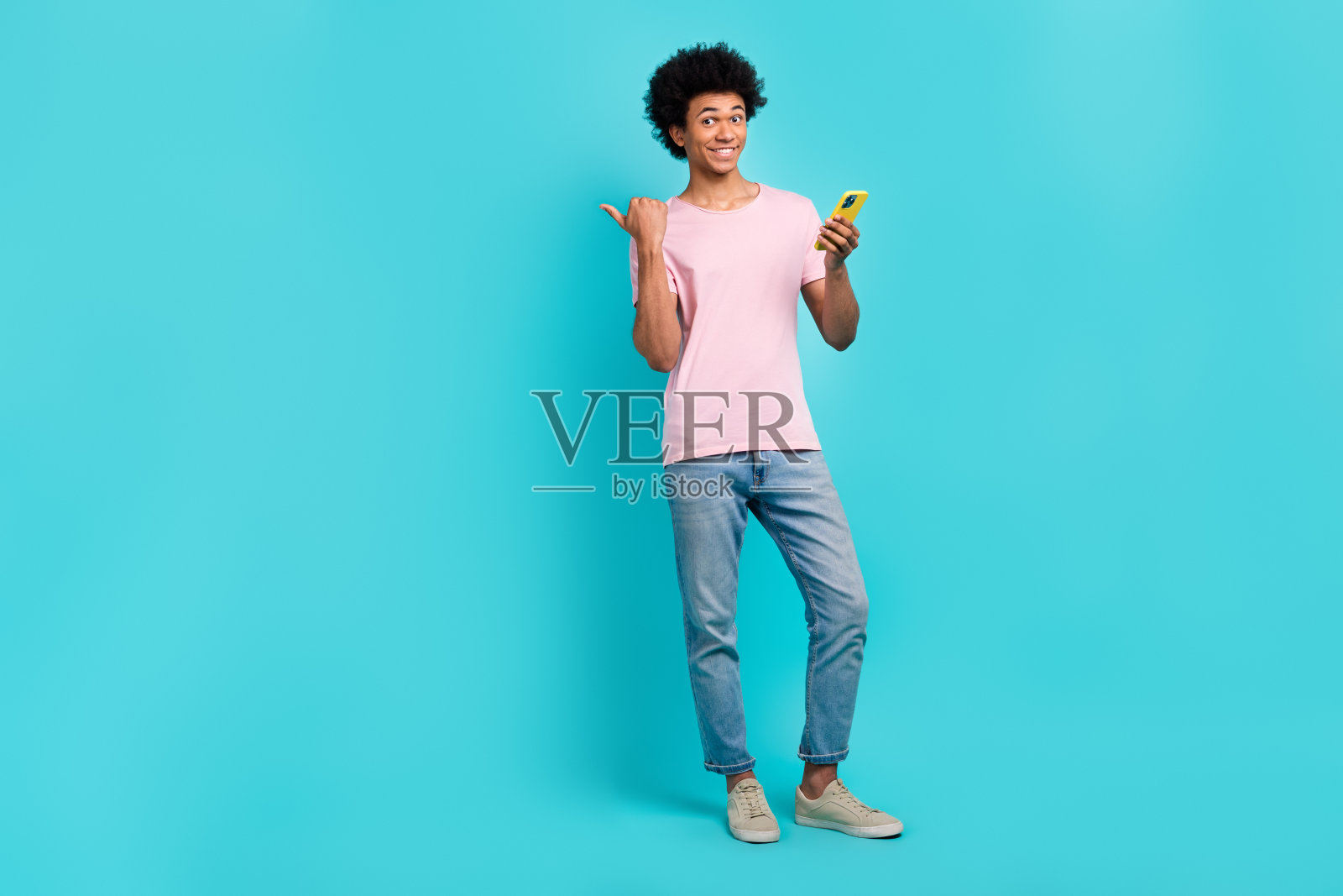 丰满的身材满意的青年男子博主骨干拿着手机直接手指空白空间订阅twitter孤立在青色背景上照片摄影图片