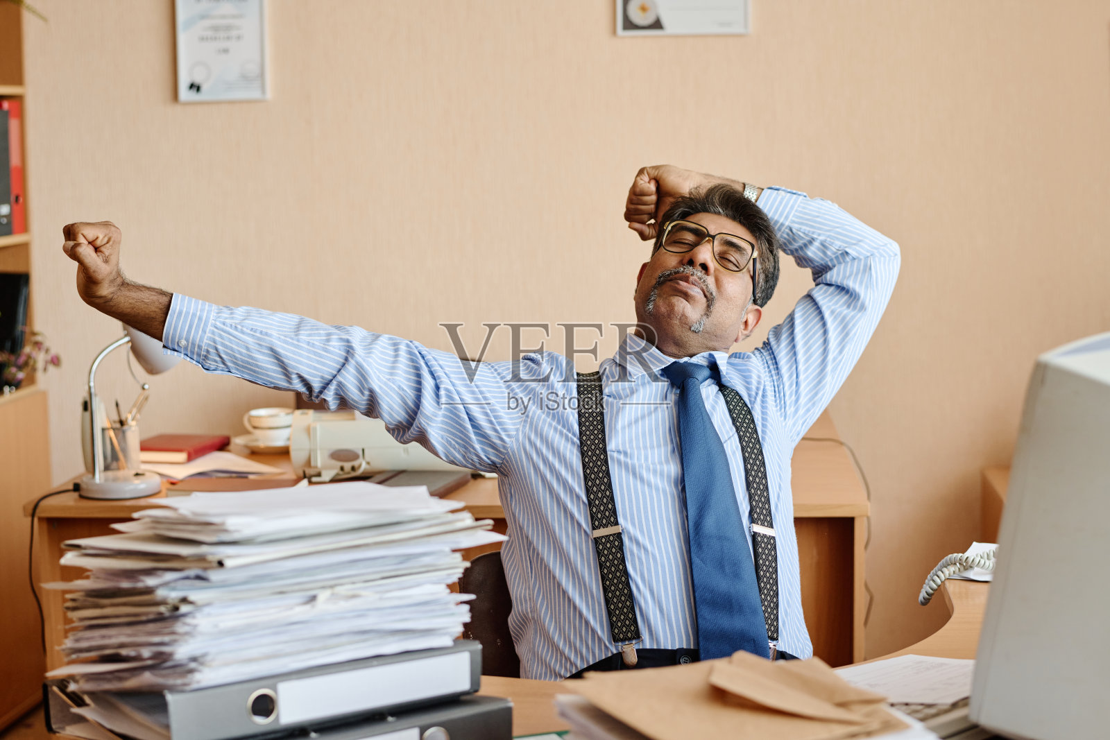 上班族在办公桌前打哈欠和伸懒腰照片摄影图片