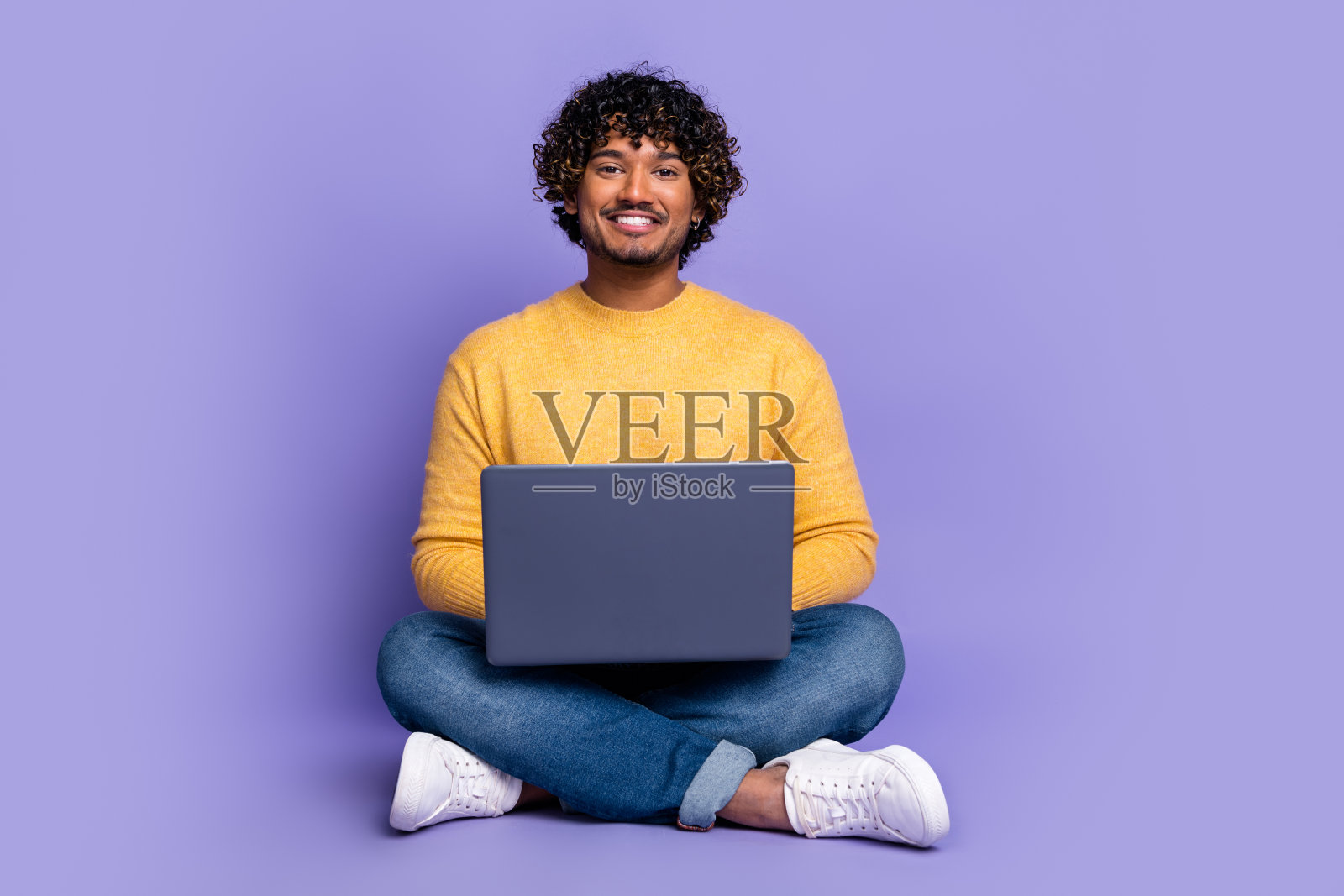 照片中的快乐男人穿着时髦的黄色衣服，在紫色的背景上使用小工具照片摄影图片