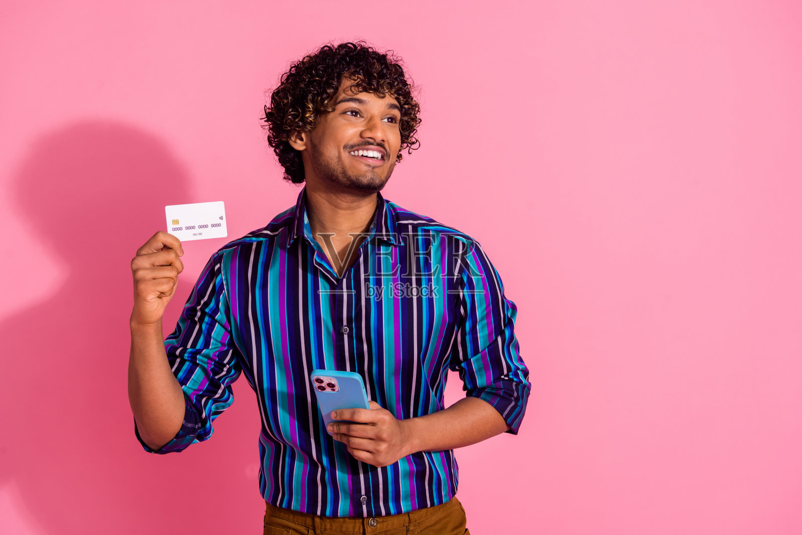 漂亮的年轻人的照片借记卡手机看起来空的空间穿衬衫孤立在粉红色的背景照片摄影图片