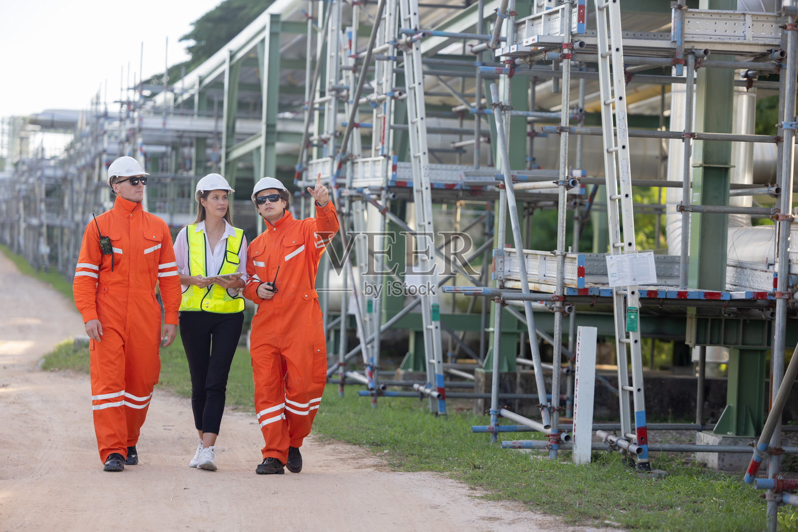 工程师们沿着炼油厂工地边走边讨论他们的工作照片摄影图片