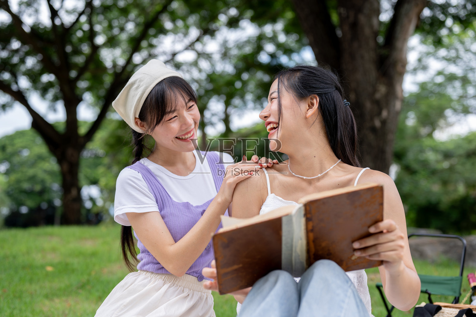 两个可爱的亚洲朋友在公园野餐时正在享受谈话和读书。照片摄影图片