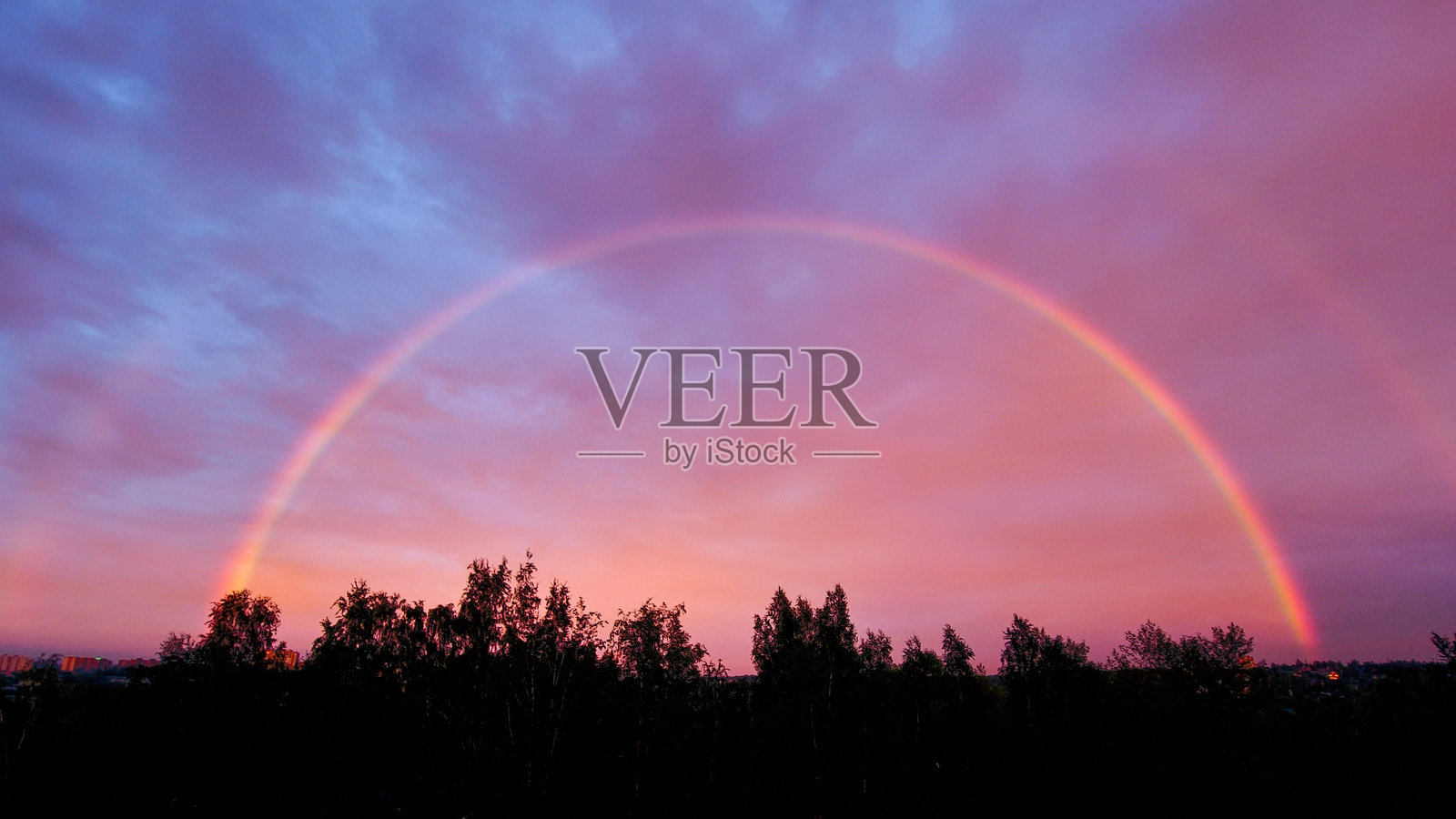 天空中雨后的彩虹，被夕阳照亮的碎片。彩虹的天空。日落时的彩虹。照片摄影图片