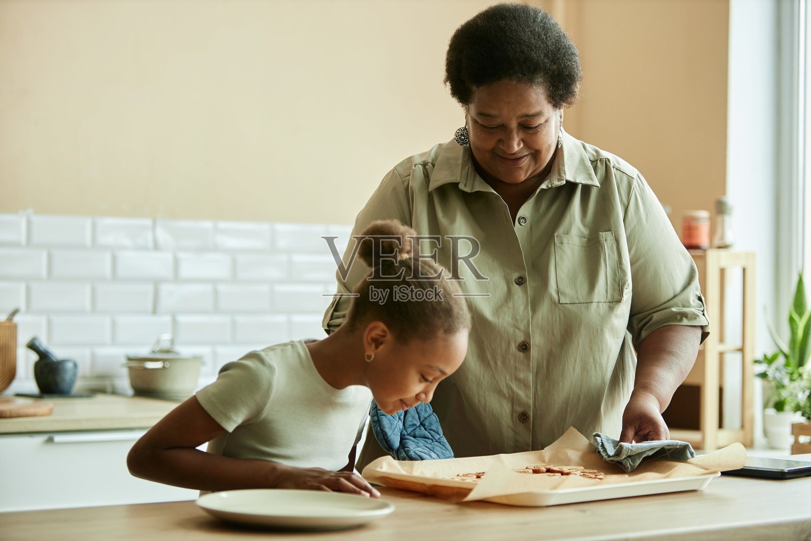 微笑的资深黑人妇女和女孩一起做自制饼干照片摄影图片