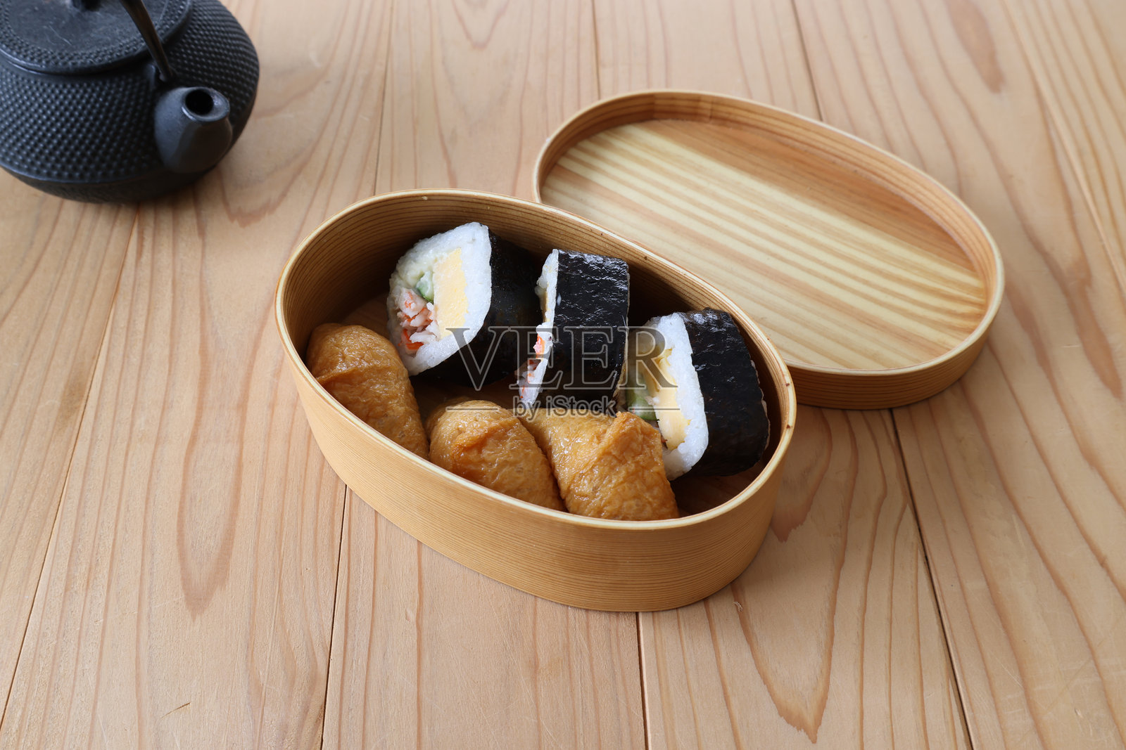 寿司卷和稻谷寿司放在木制的饭盒里，放在木制的桌子上。照片摄影图片