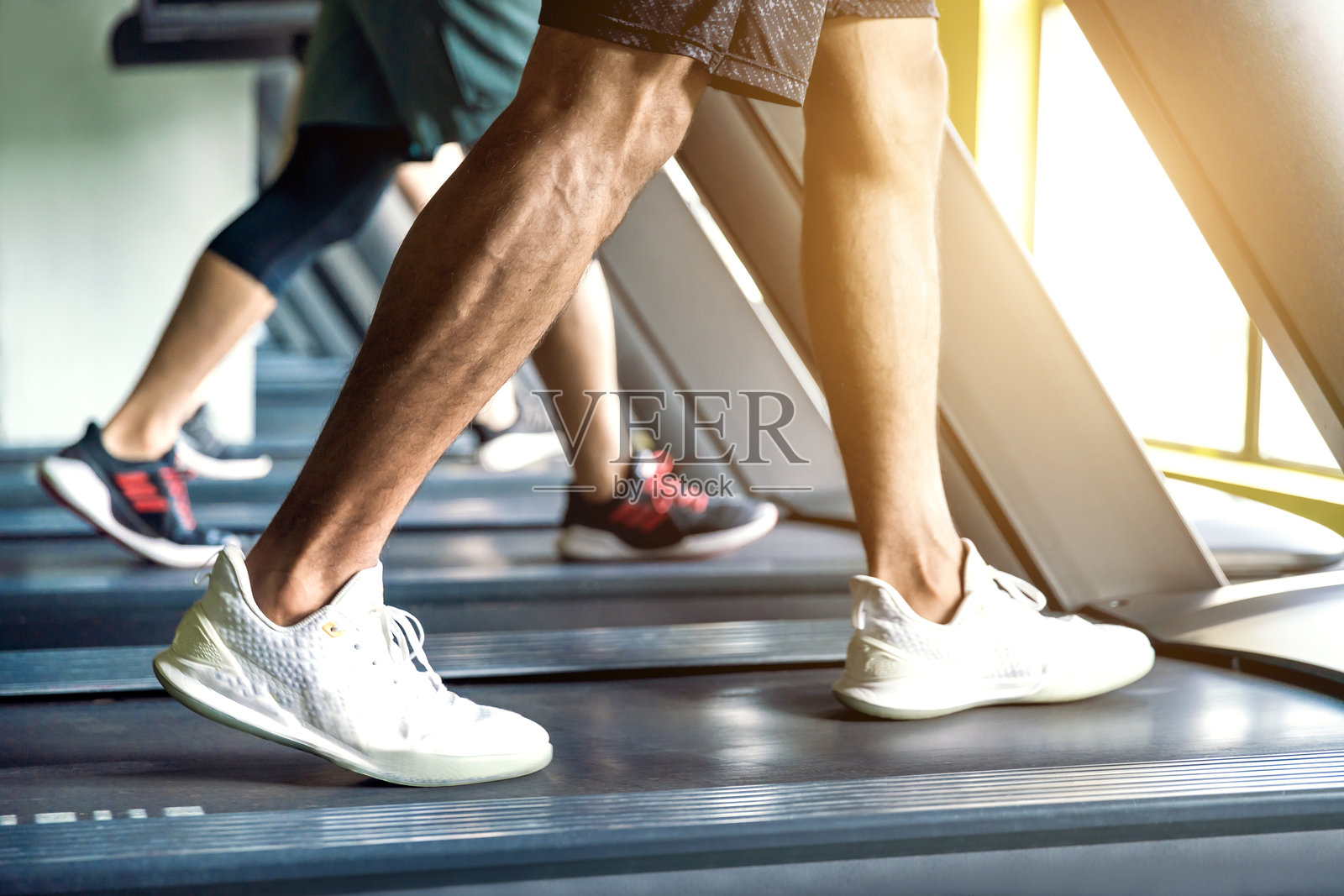 男人们在健身房的跑步机上锻炼。照片摄影图片