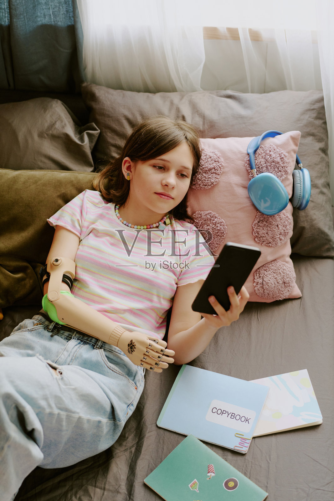 十几岁的女孩用智能手机看书照片摄影图片