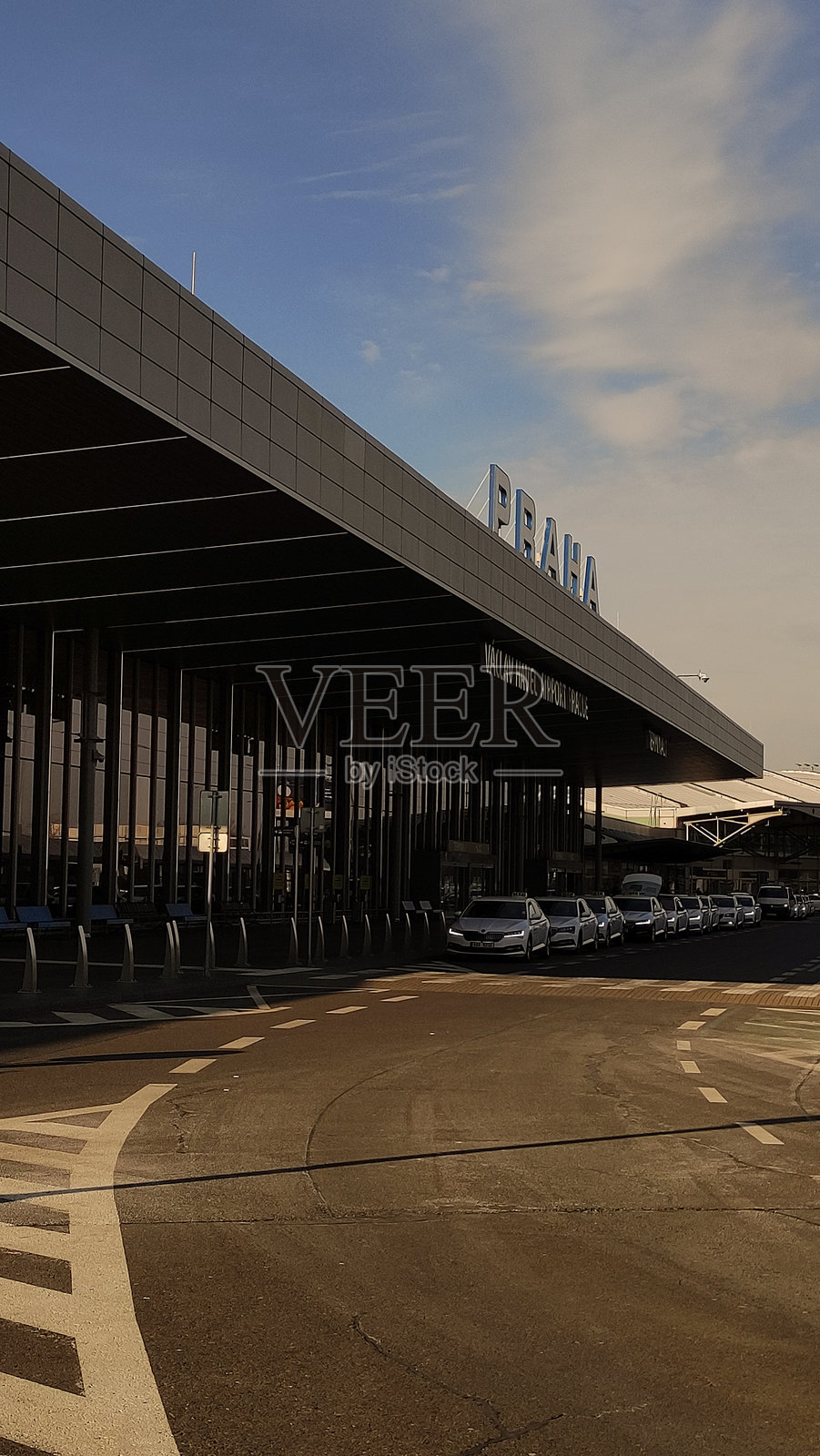 前景是一座候机楼，前方有汽车在行驶。照片摄影图片