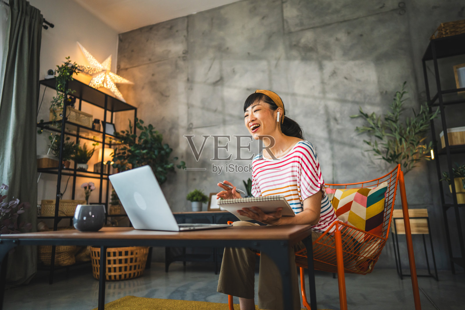 成熟的日本女人戴着耳机，用笔记本电脑进行视频通话照片摄影图片
