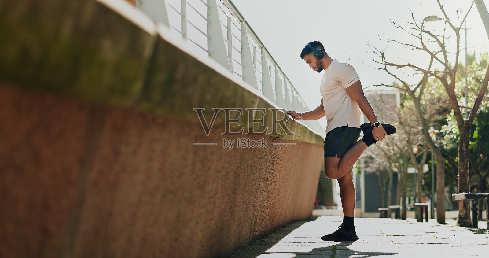 健身，在城市里用耳机热身腿部，用音乐或收音机锻炼身体。运动员，人和音频声音户外跑步挑战，性能和健康照片摄影图片