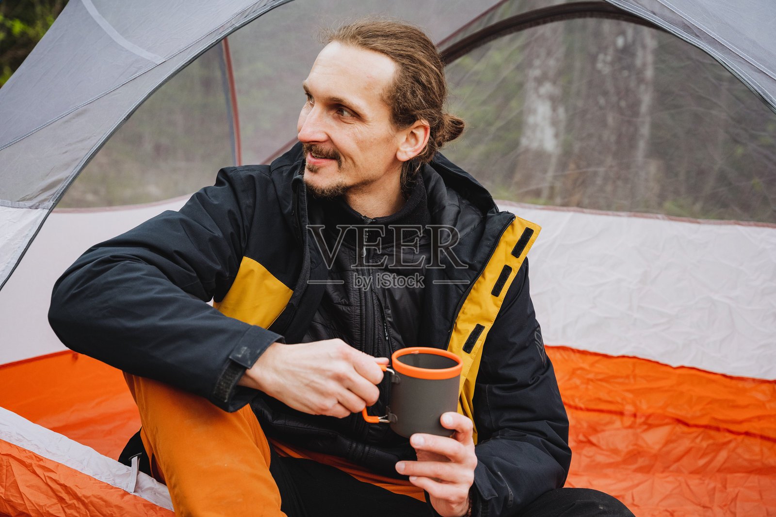 男人在帐篷里微笑着，端着一杯咖啡，享受着休闲和放松照片摄影图片