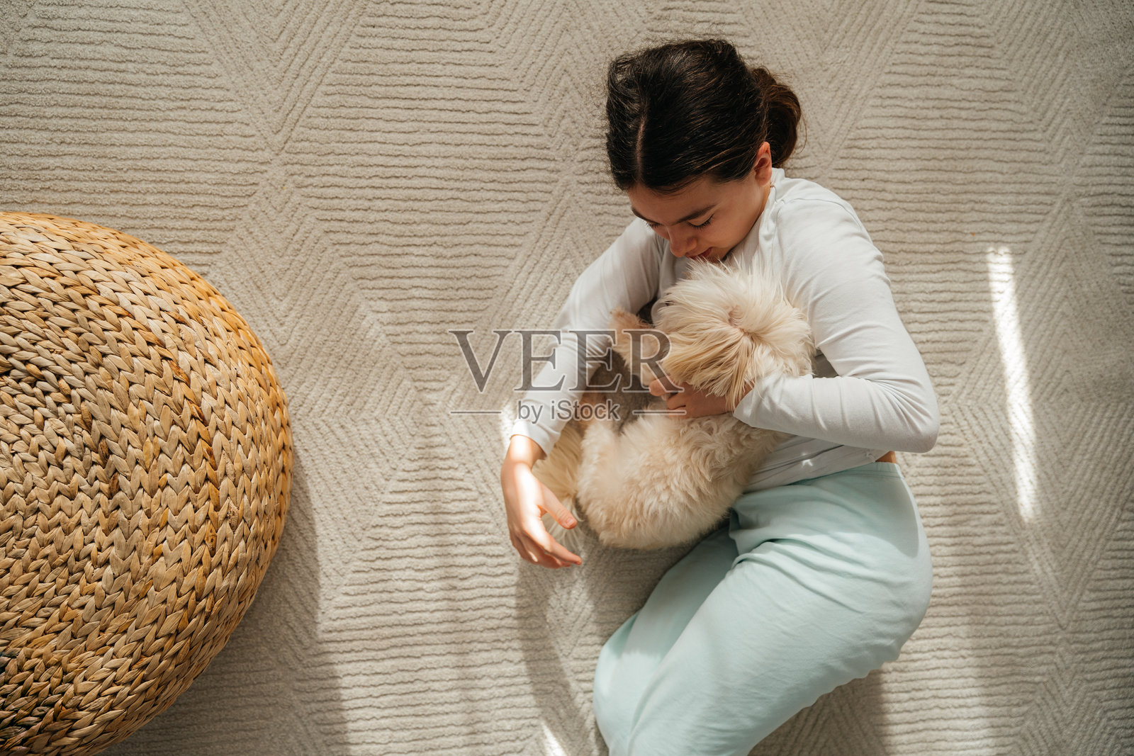 一个十几岁的女孩躺在家里的地毯上和她的狗玩耍照片摄影图片