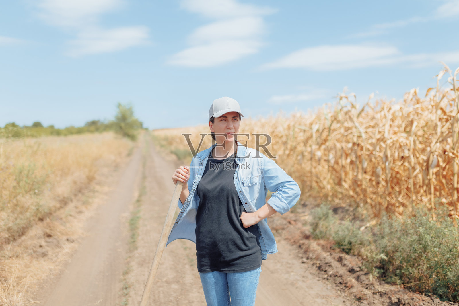 女农民戴着帽子和牛仔衬衫，享受着太阳的温暖照片摄影图片