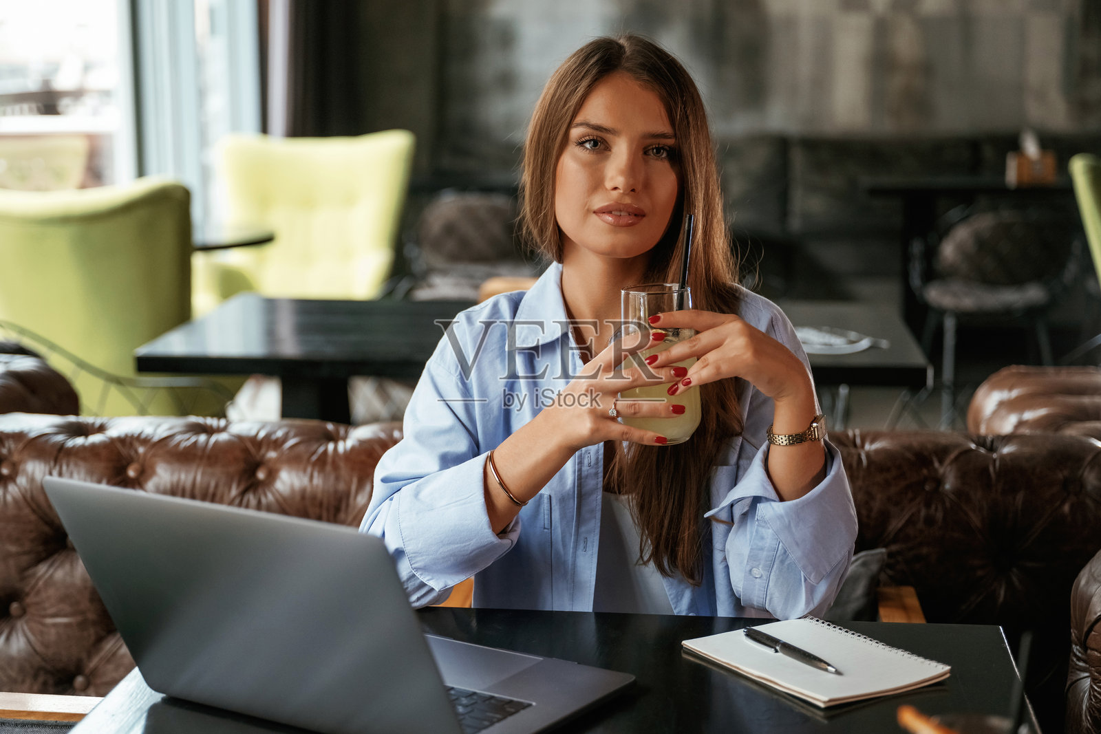 享受这杯饮料。拿着笔记本电脑的美女在酒吧里照片摄影图片