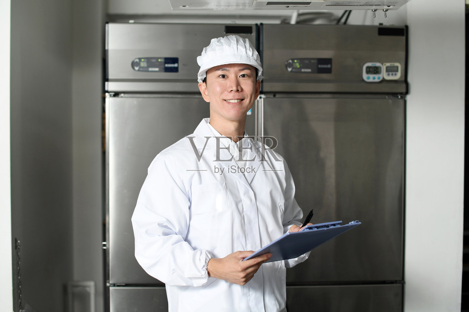 穿着卫生服的亚洲男子检查厨房设备照片摄影图片