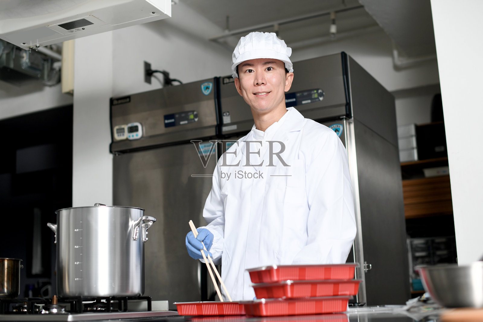 一名穿着干净西装的男厨师将食材装进便当盒照片摄影图片