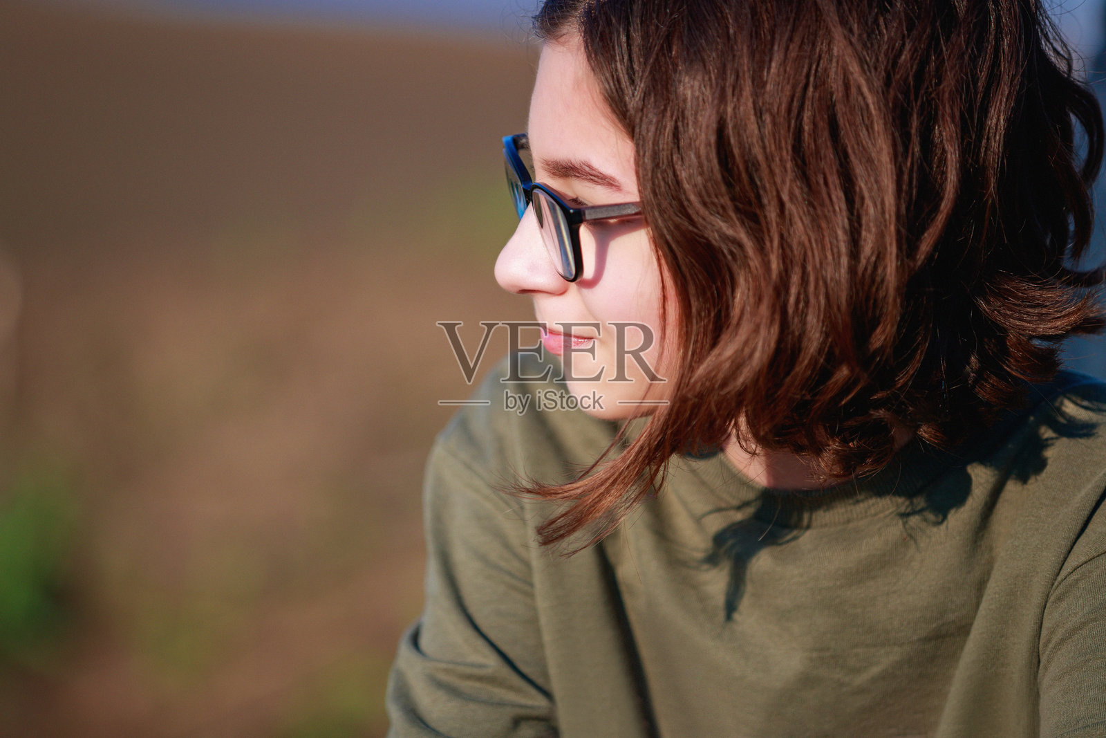 一个美丽的青春期前的棕色头发的女孩，在一个阳光明媚的日子坐在乡下的户外照片摄影图片