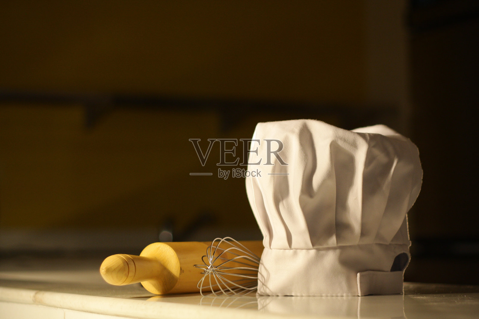 厨师帽子的特写，桌子上有铁丝打蛋器和擀面杖照片摄影图片