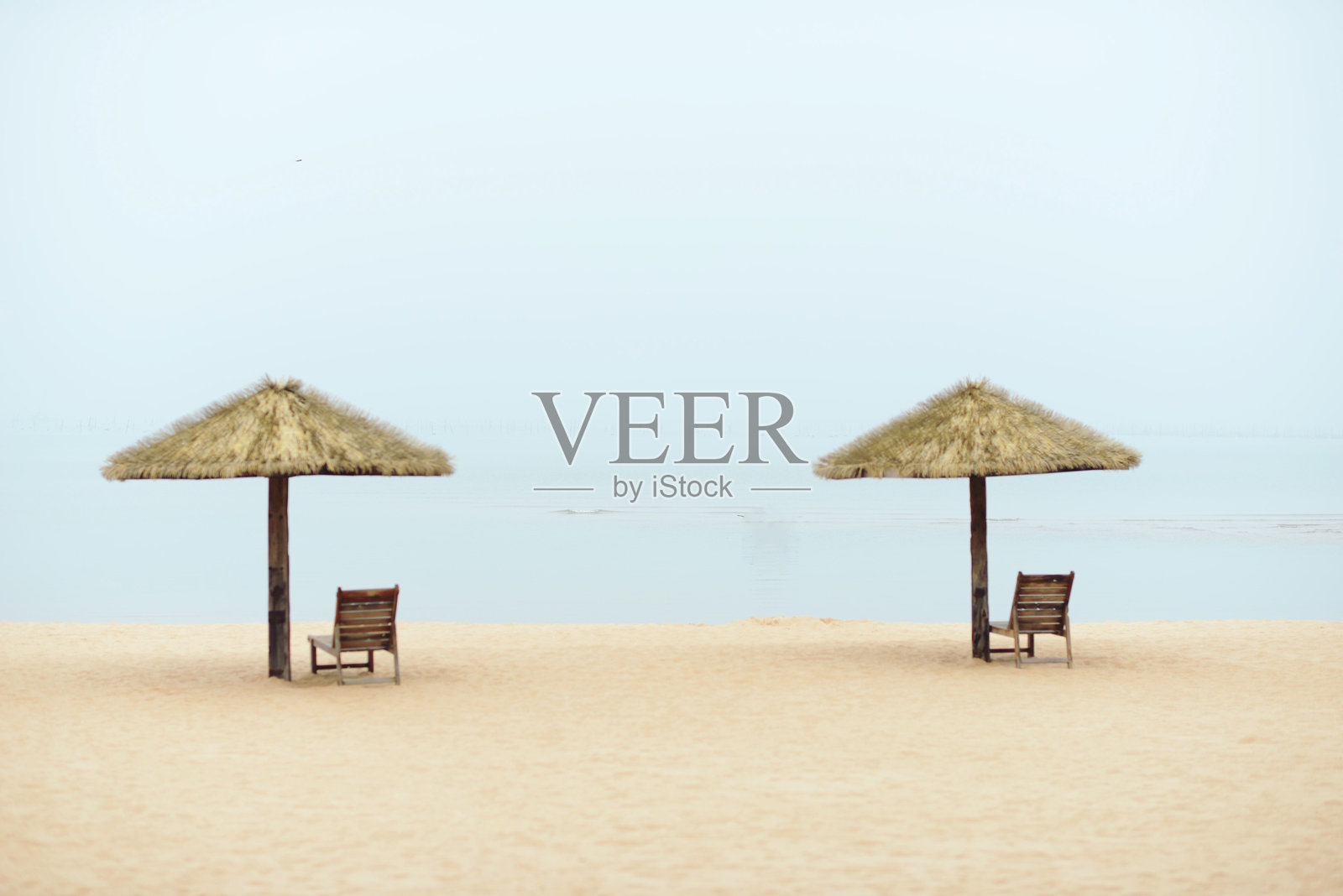 沙滩上的茅草屋顶躺椅照片摄影图片