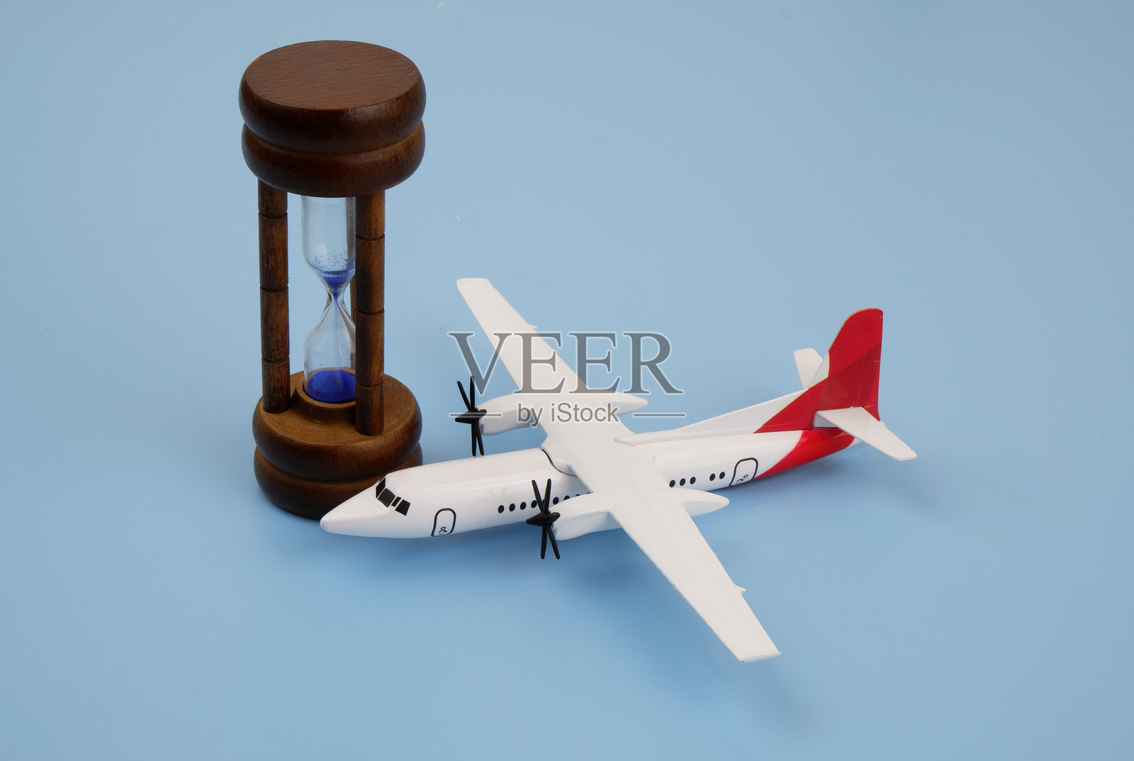 飞机模型与沙漏在蓝色背景。照片摄影图片