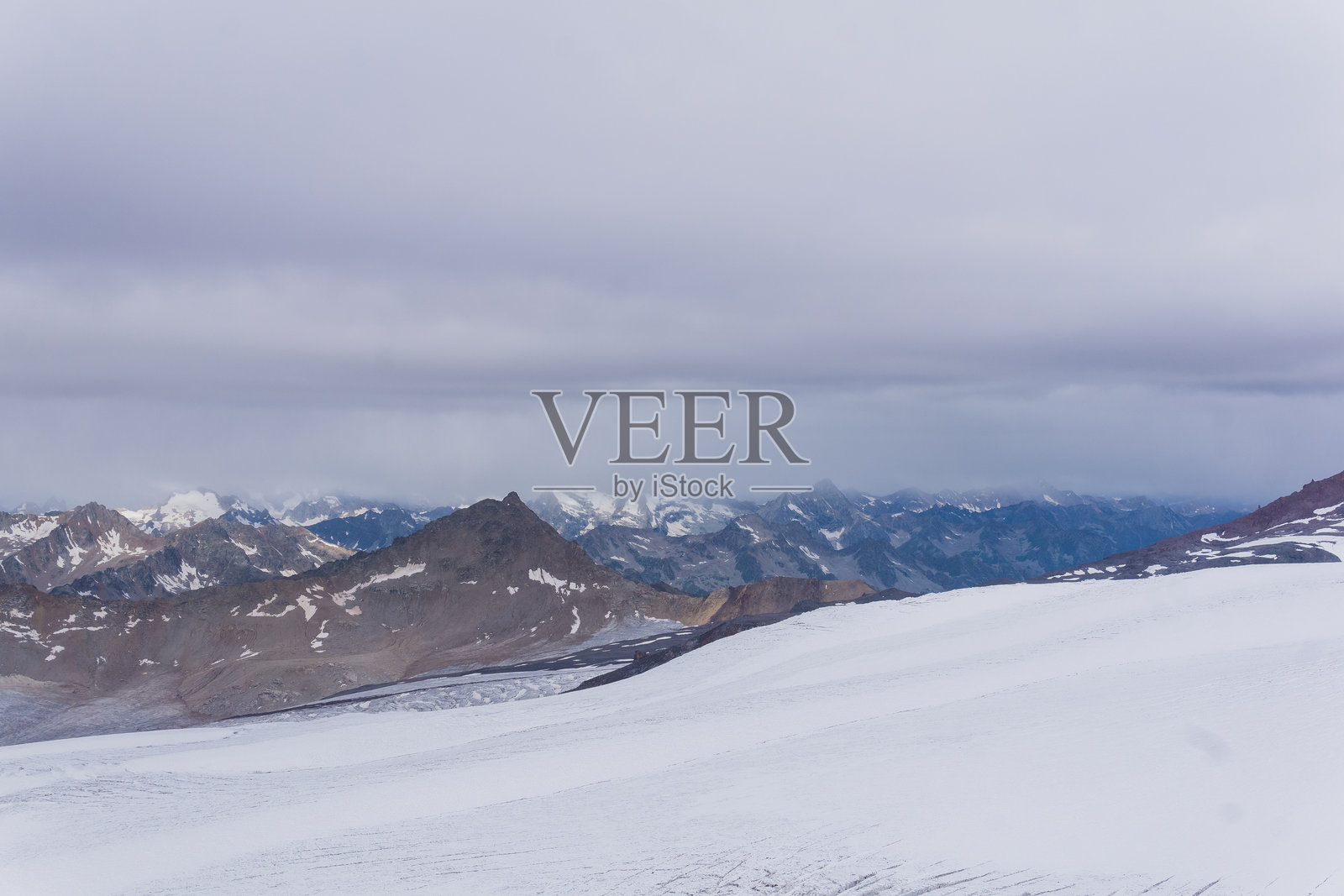 从厄尔布鲁士山斜坡上的冰川上俯瞰云层之上的高山照片摄影图片